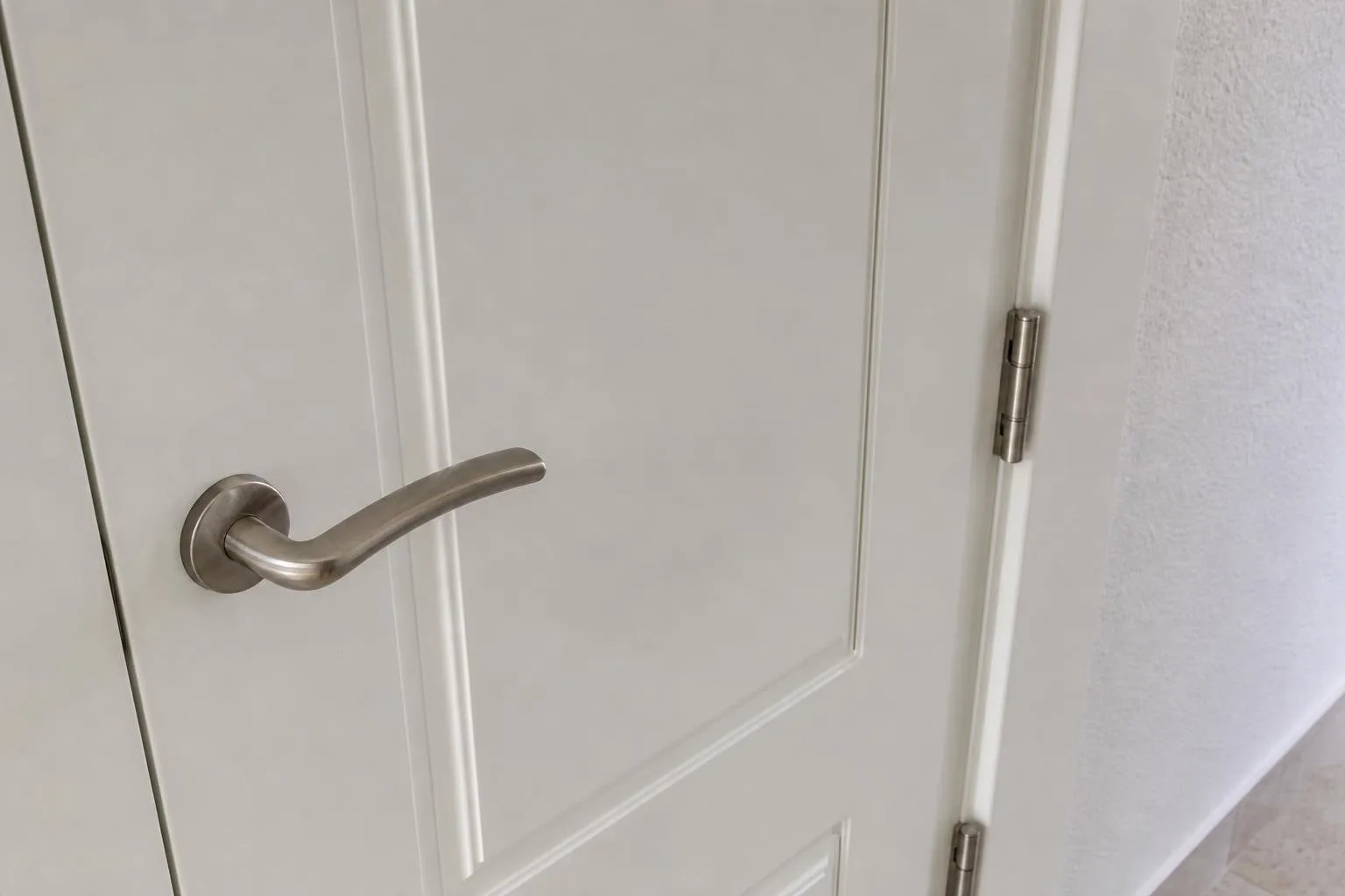 Detalle de manilla y bisagras en una puerta blanca