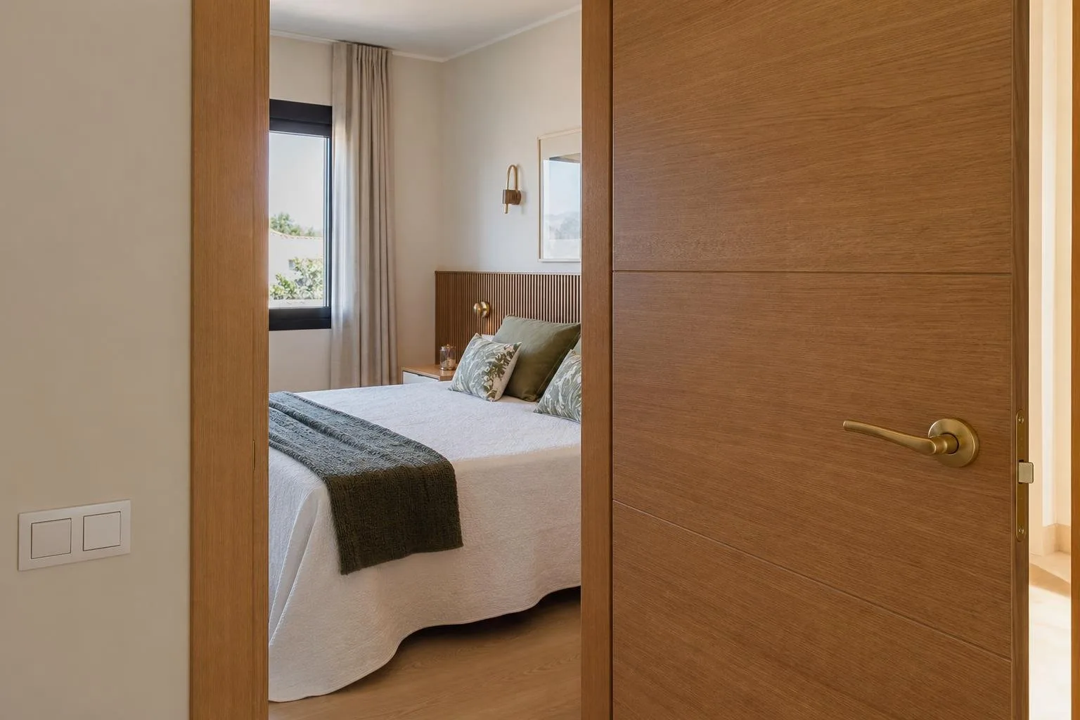 Puerta interior de roble abierta hacia un dormitorio