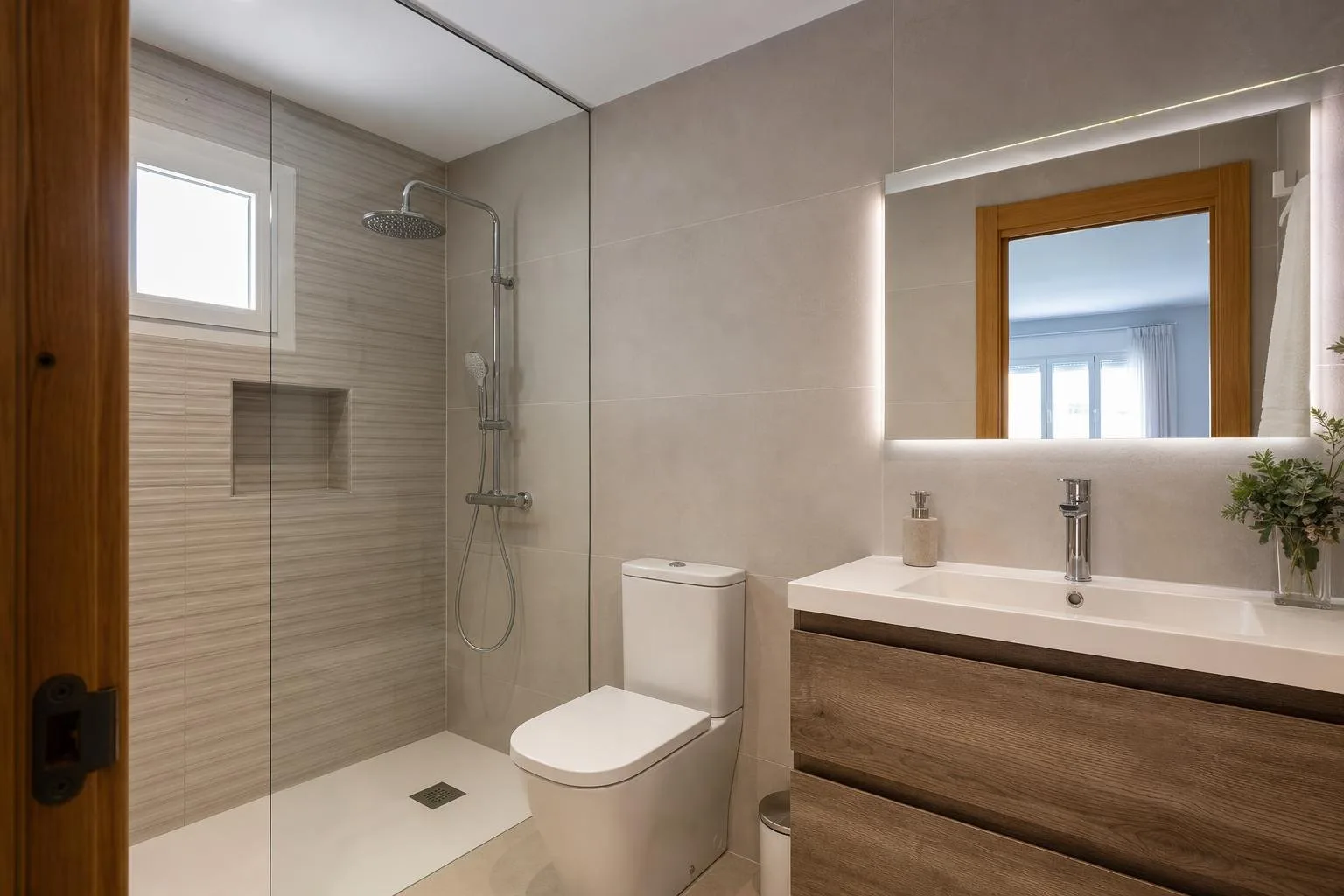 Baño de piso reformado con ducha y azulejo neutro